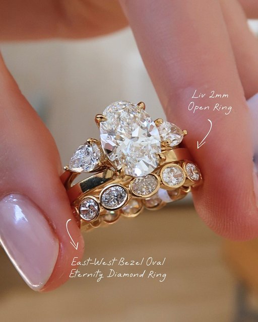 Oval on oval is always a good idea. The stack: 
💎ER Setting: Luxe Opera Three Stone Diamond Ring
💎First Band: Liv 2mm Open Ring
💎Second Band: East West Bezel Oval Diamond Eternity Ring